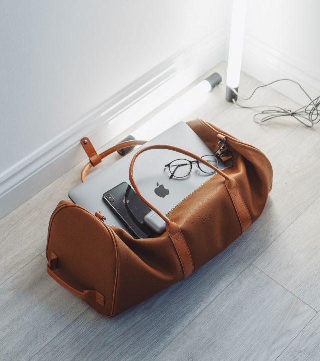 tan leather travel bag with macbook iphone and reading glasses 